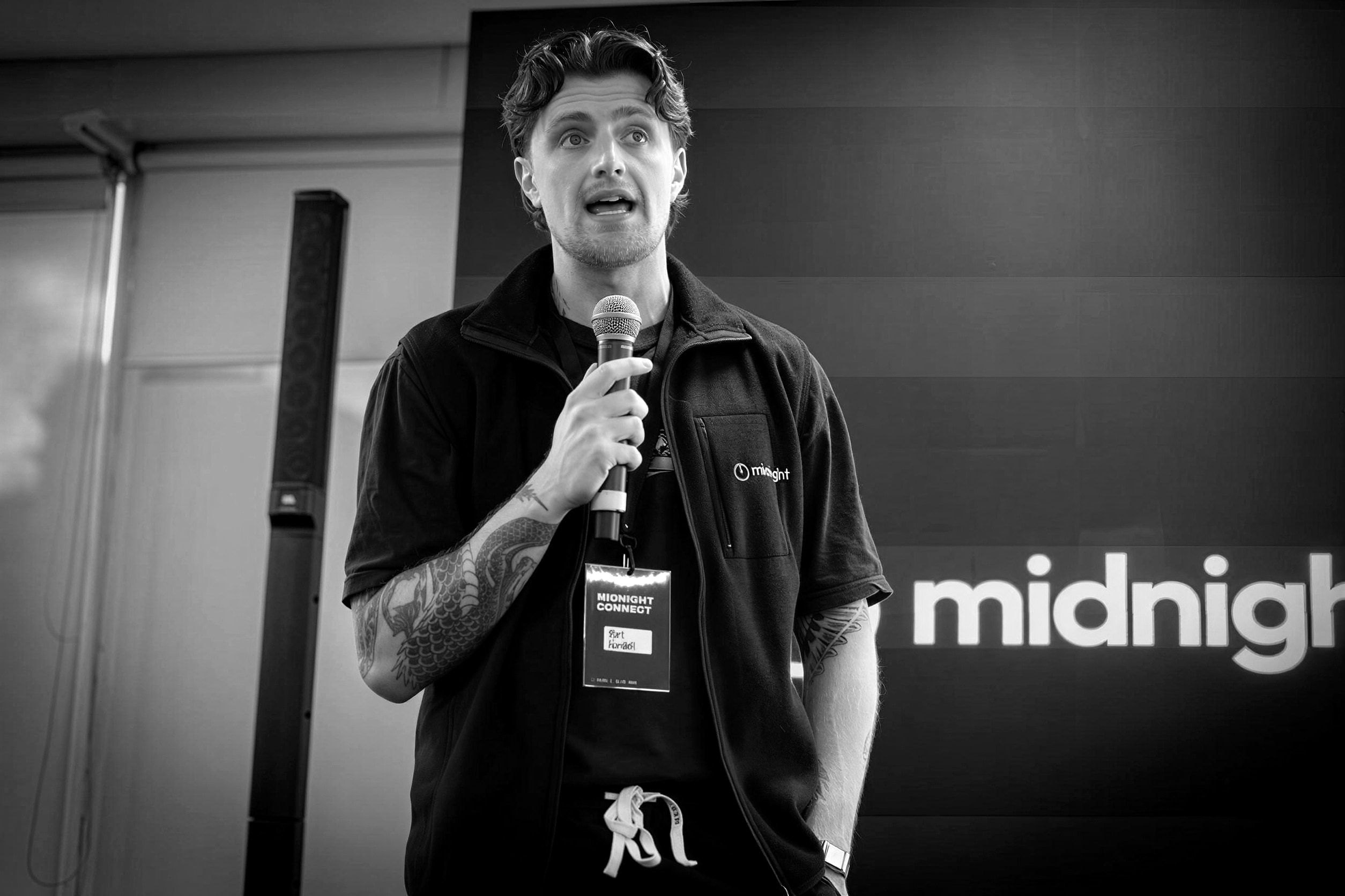 Tom speaking on stage at Midnight Connect, microphone in hand